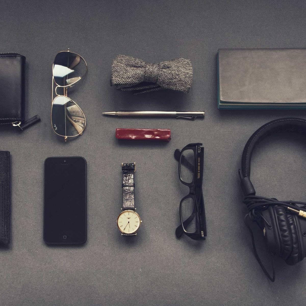 Flat lay of everyday carry: wallet, glasses, watch, and headphones