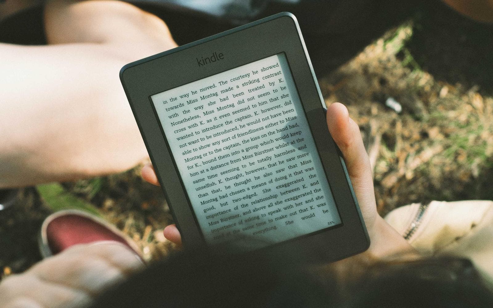 Hands holding an e-reader outdoors